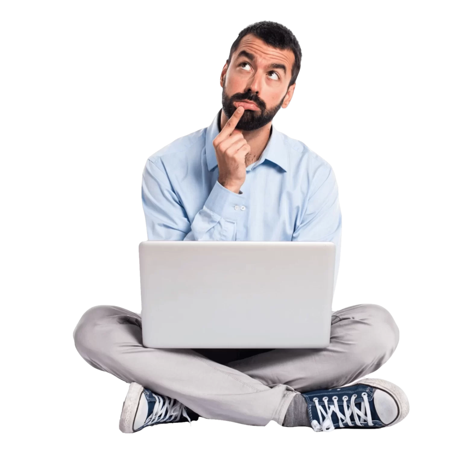 un homme pensif en chemise bleu, pantalon gris, converse bleu, assis en tailleur avec un ordinateur portable sur les genoux. Il est pensif et se questionne.