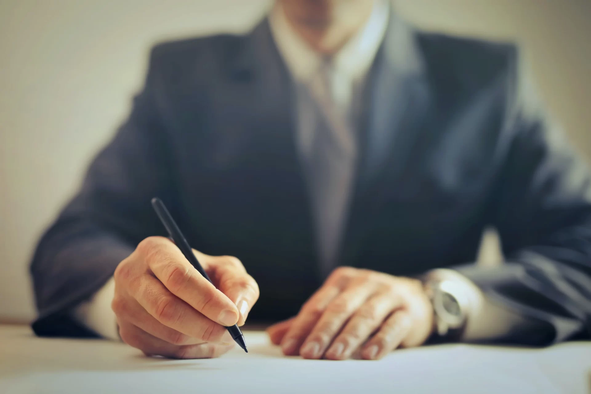 un expert comptable en costume trois pièces tenant un stylo dans sa main droite pour signer un document.